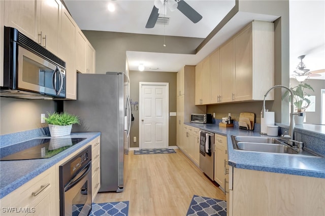 kitchen with ceiling fan, appliances with stainless steel finishes, light wood-type flooring, light brown cabinetry, and sink