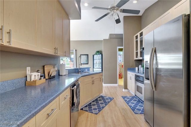 kitchen featuring appliances with stainless steel finishes, lofted ceiling, light hardwood / wood-style floors, sink, and ceiling fan