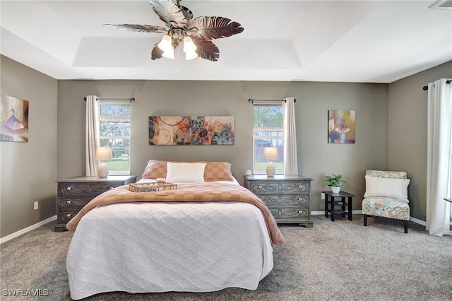 bedroom featuring ceiling fan, a tray ceiling, and carpet floors