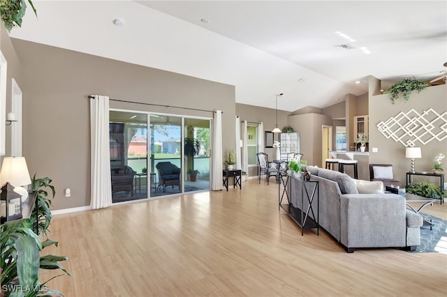 living room with plenty of natural light, vaulted ceiling, and light wood-type flooring