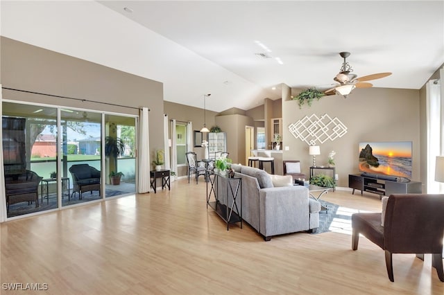 living room featuring light wood-type flooring, ceiling fan, and vaulted ceiling