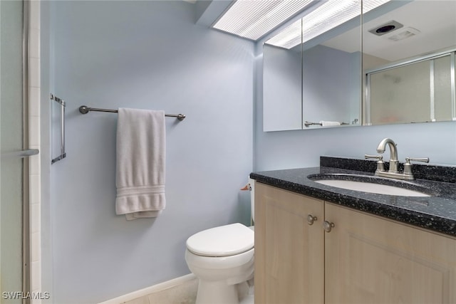 bathroom featuring toilet, vanity, tile patterned flooring, and walk in shower