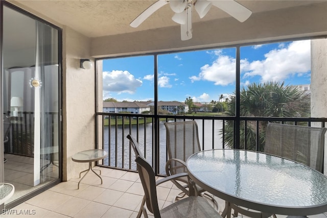 sunroom featuring ceiling fan and a water view