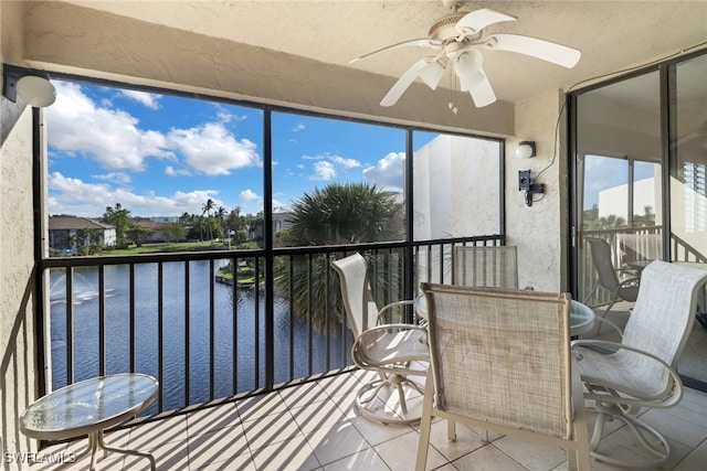 sunroom / solarium with ceiling fan and a water view