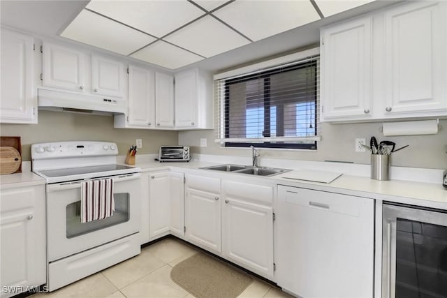 kitchen with white appliances, wine cooler, under cabinet range hood, white cabinetry, and a sink