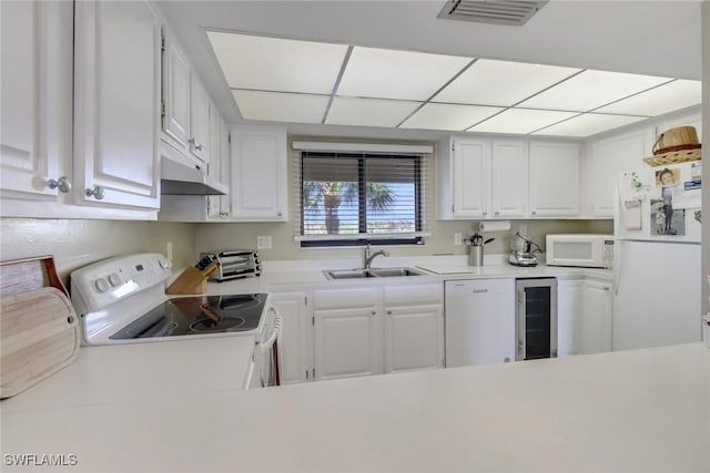 kitchen featuring beverage cooler, white appliances, a sink, visible vents, and light countertops