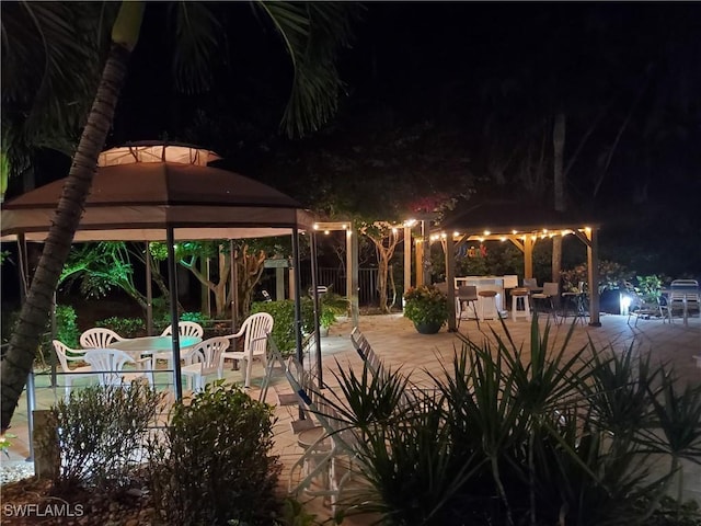 pool at night featuring a patio area and a gazebo