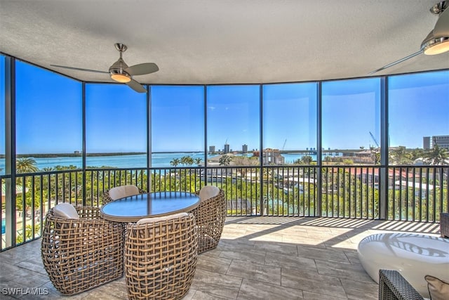 sunroom featuring ceiling fan and a water view