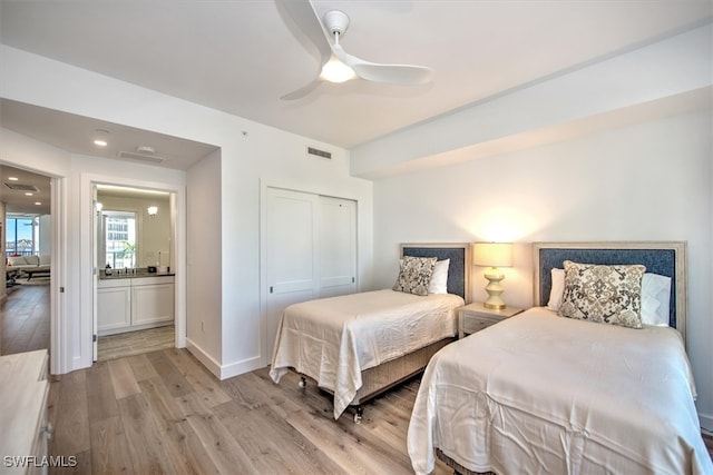 bedroom featuring ceiling fan, ensuite bath, a closet, and light wood-type flooring