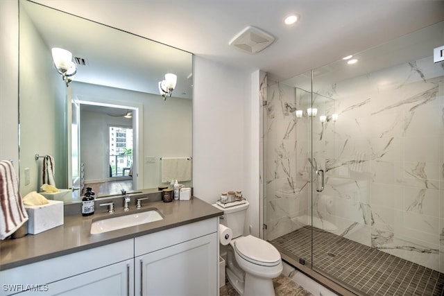 bathroom with toilet, vanity, and a shower with shower door