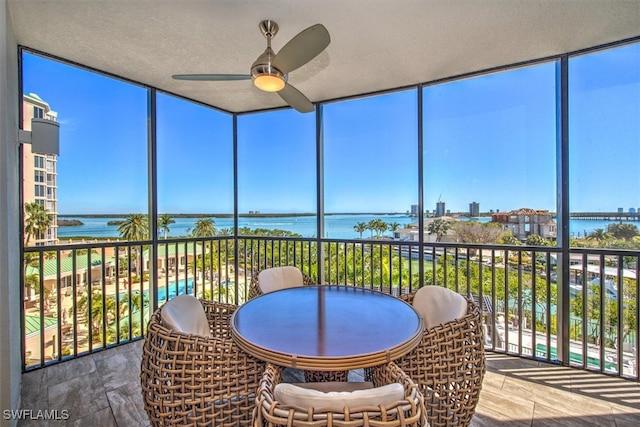 sunroom / solarium featuring a water view and ceiling fan