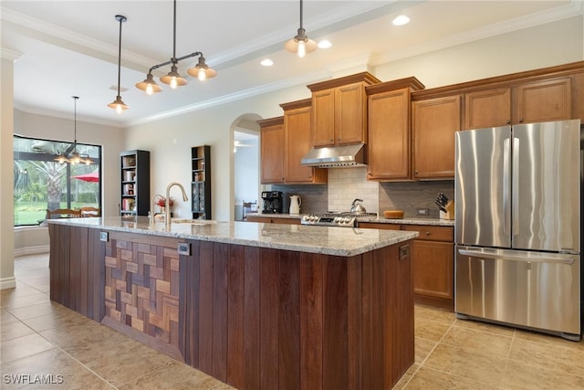 kitchen featuring stainless steel appliances, crown molding, hanging light fixtures, and a center island with sink