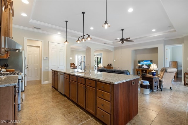 kitchen featuring sink, stainless steel appliances, a raised ceiling, decorative light fixtures, and a kitchen island with sink