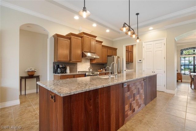 kitchen featuring a center island with sink, sink, hanging light fixtures, tasteful backsplash, and stainless steel appliances