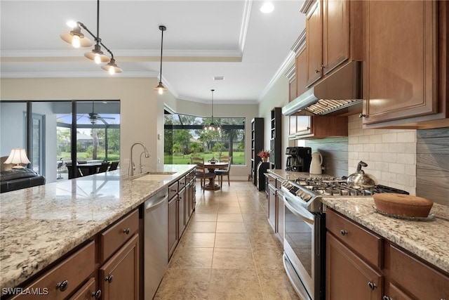 kitchen with light stone countertops, appliances with stainless steel finishes, hanging light fixtures, and sink