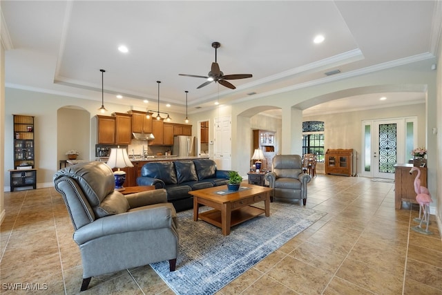 living room with a raised ceiling, ceiling fan, and ornamental molding