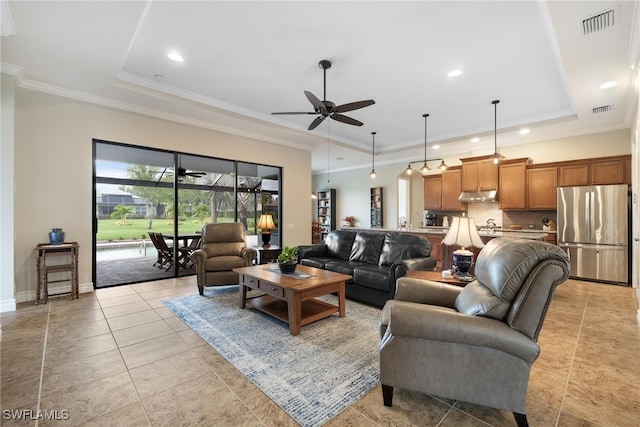 tiled living room featuring a tray ceiling, ceiling fan, and ornamental molding