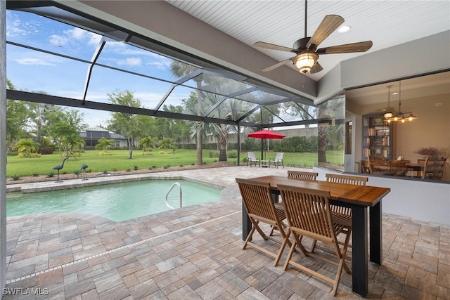 view of swimming pool featuring a lawn, glass enclosure, ceiling fan, and a patio area