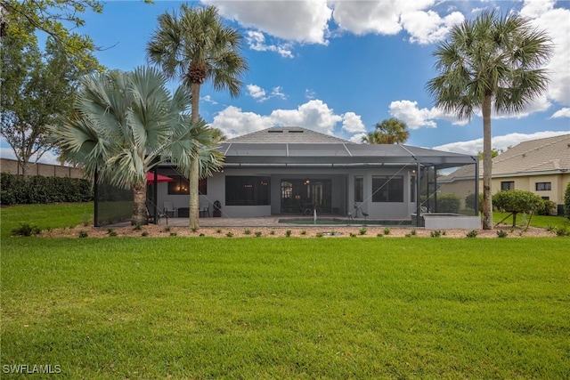 rear view of house with glass enclosure, a patio area, and a yard