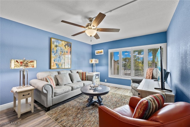 living room with a textured ceiling, hardwood / wood-style flooring, and ceiling fan