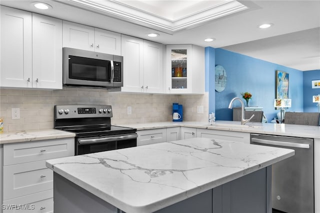 kitchen with white cabinetry, appliances with stainless steel finishes, and light stone countertops