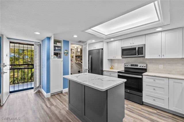 kitchen featuring white cabinets, light hardwood / wood-style floors, a kitchen island, and appliances with stainless steel finishes