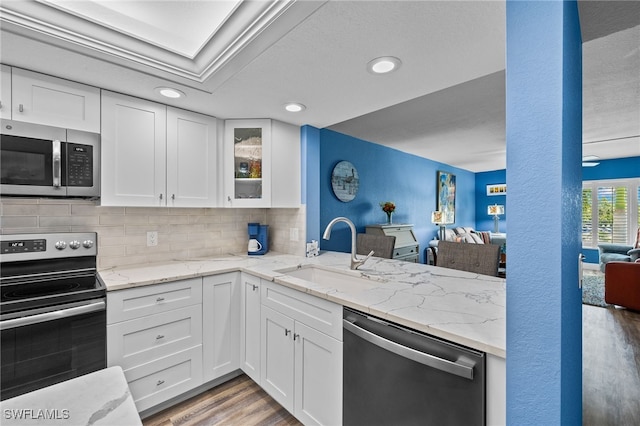 kitchen with white cabinets, light wood-type flooring, appliances with stainless steel finishes, and sink