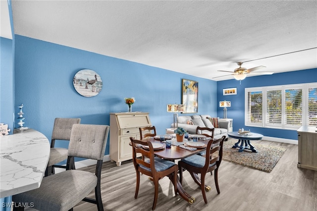 dining area with a textured ceiling, light wood-type flooring, and ceiling fan