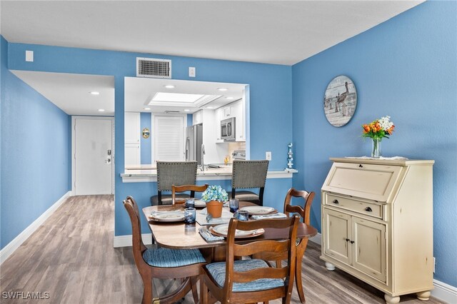 dining area featuring light wood-type flooring and sink