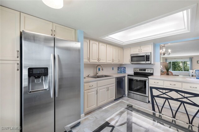 kitchen with appliances with stainless steel finishes, sink, tasteful backsplash, and light tile patterned floors