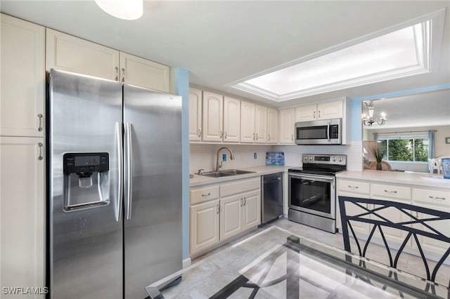 kitchen with light countertops, appliances with stainless steel finishes, a sink, and decorative backsplash