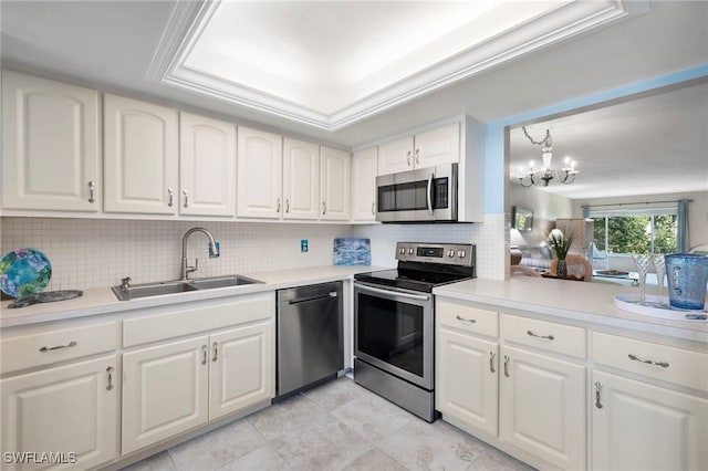 kitchen featuring stainless steel appliances, pendant lighting, decorative backsplash, sink, and white cabinets