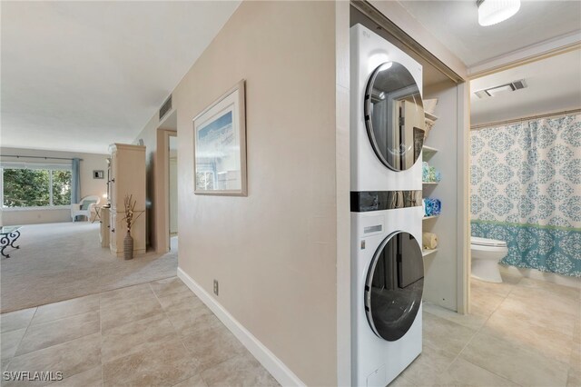 washroom featuring light colored carpet and stacked washer / drying machine