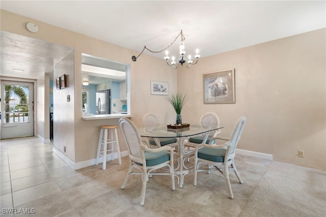 dining space featuring light tile patterned floors, baseboards, and an inviting chandelier