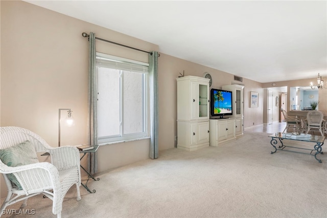 living room with an inviting chandelier, visible vents, and light colored carpet