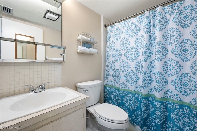 bathroom featuring toilet, tasteful backsplash, and vanity