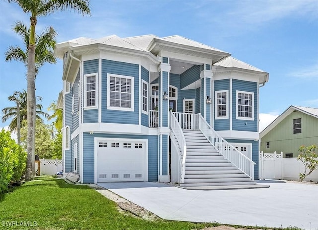 view of front of property featuring covered porch, a garage, and a front lawn