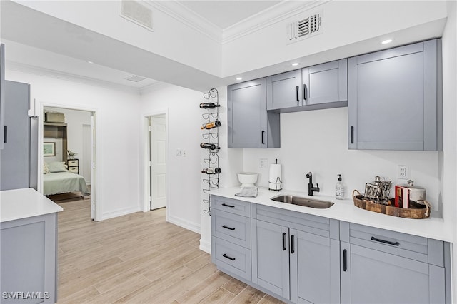 kitchen with gray cabinets, sink, light hardwood / wood-style floors, and ornamental molding