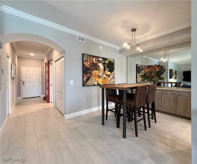 dining room featuring light wood-type flooring and crown molding