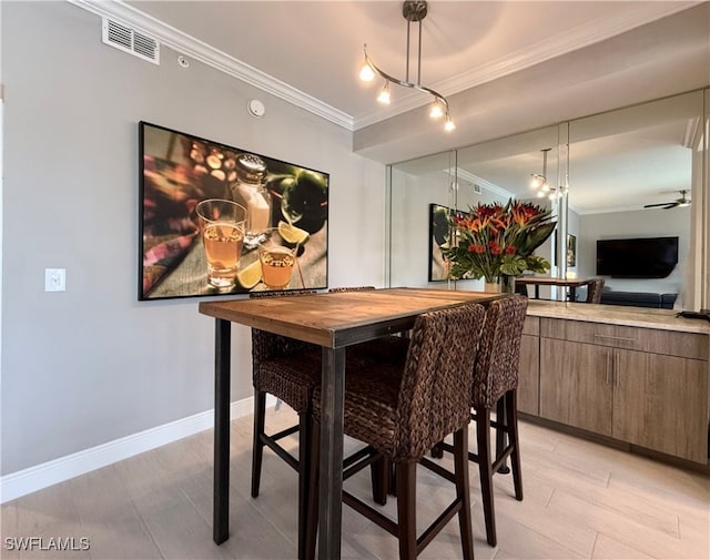 dining room with ornamental molding, light wood-type flooring, and ceiling fan