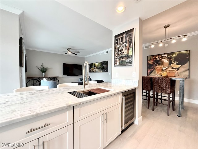 kitchen with crown molding, sink, white cabinets, beverage cooler, and ceiling fan