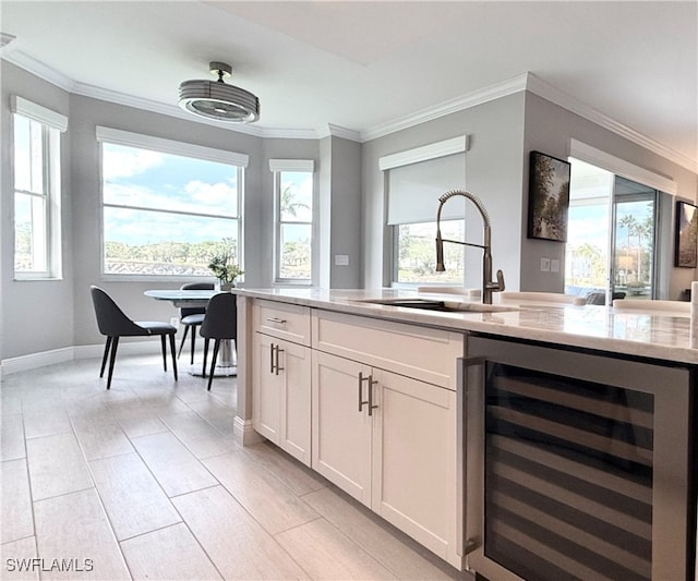 kitchen with white cabinets, ornamental molding, sink, and wine cooler