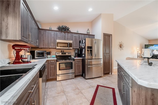 kitchen featuring appliances with stainless steel finishes, dark brown cabinets, and lofted ceiling