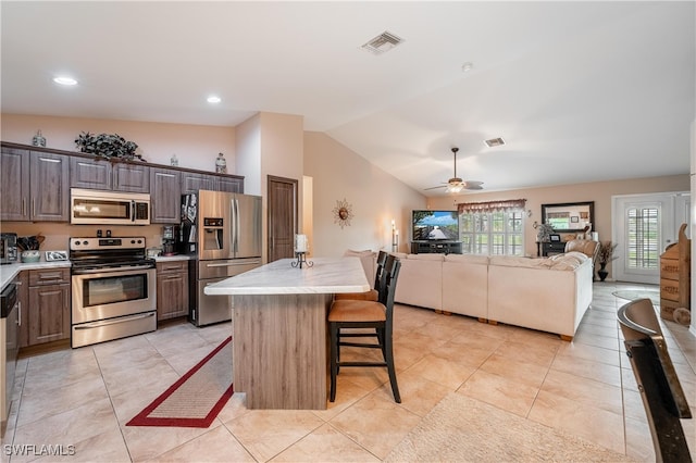 kitchen featuring a kitchen breakfast bar, a kitchen island, vaulted ceiling, and appliances with stainless steel finishes