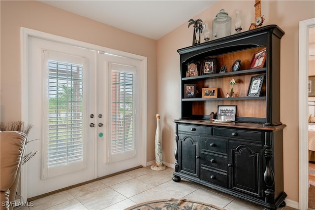 entryway featuring french doors, light tile patterned floors, and lofted ceiling