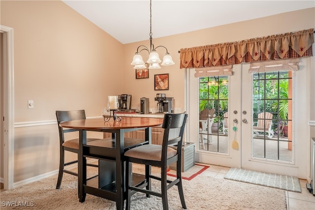 tiled dining room featuring french doors, a chandelier, and lofted ceiling