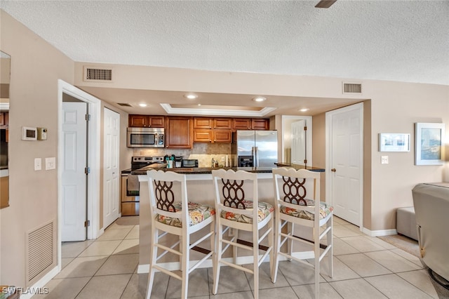 kitchen featuring a kitchen island, appliances with stainless steel finishes, light tile patterned flooring, and a breakfast bar area