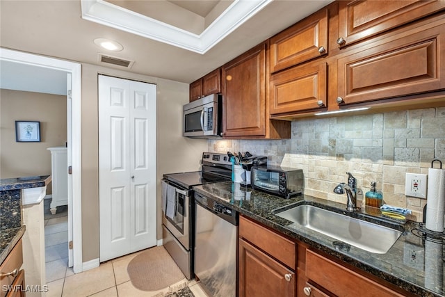 kitchen featuring light tile patterned flooring, sink, appliances with stainless steel finishes, dark stone countertops, and backsplash