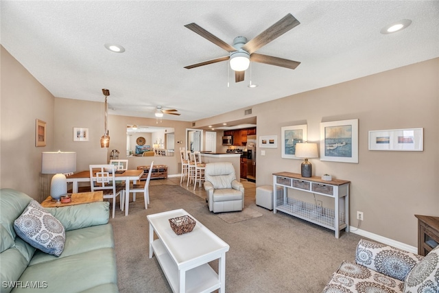 living room with ceiling fan, a textured ceiling, and light colored carpet