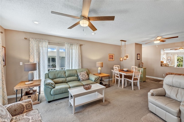 living room featuring a textured ceiling, light colored carpet, and ceiling fan with notable chandelier